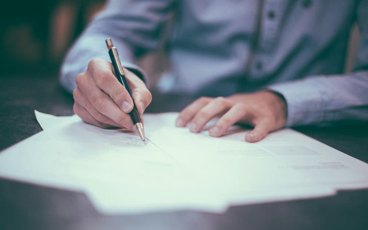 A man writing an application by hand at a desk