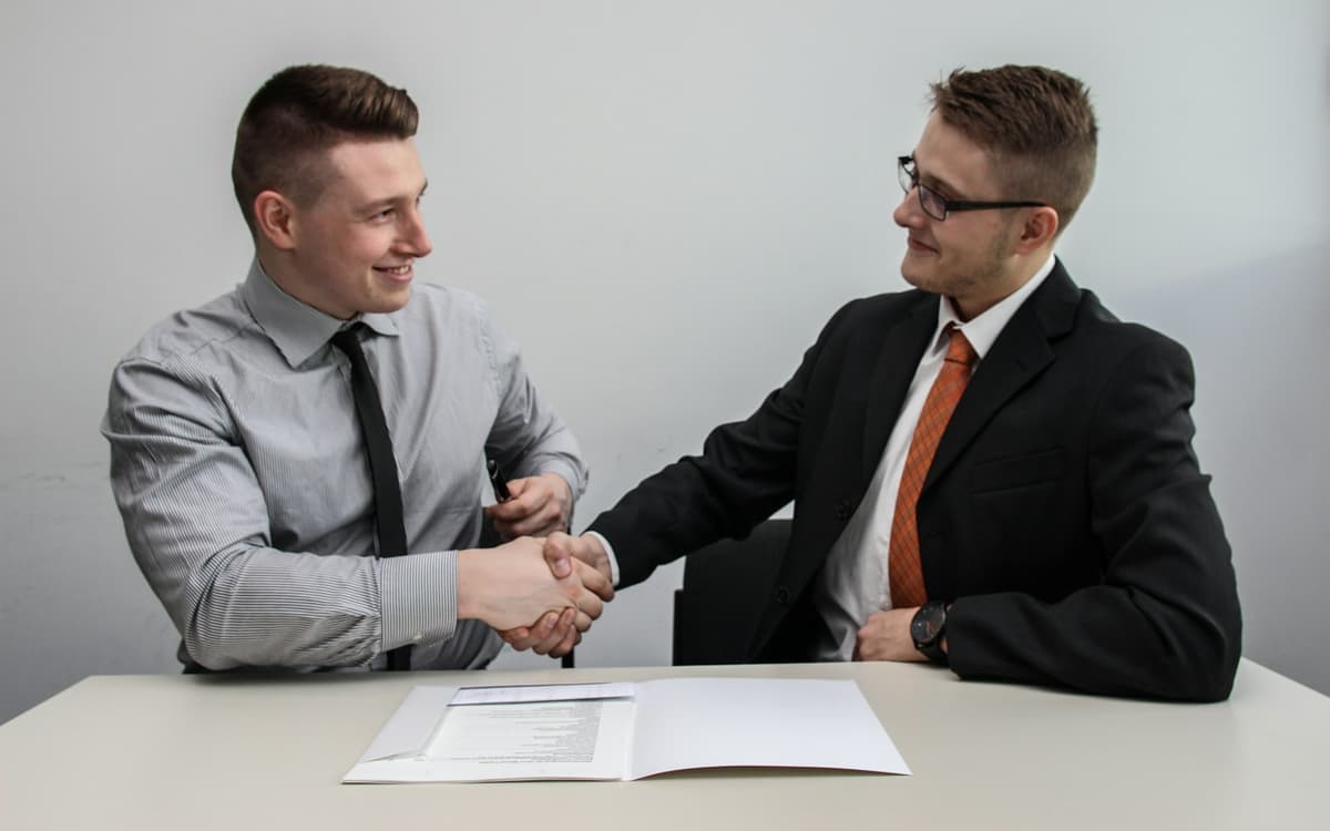 Two business partners shaking hands over a signed agreement