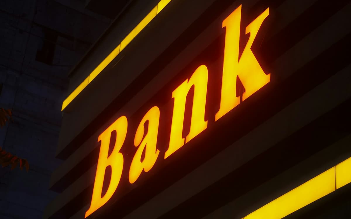 An illuminated sign reading “Bank” on a building at night