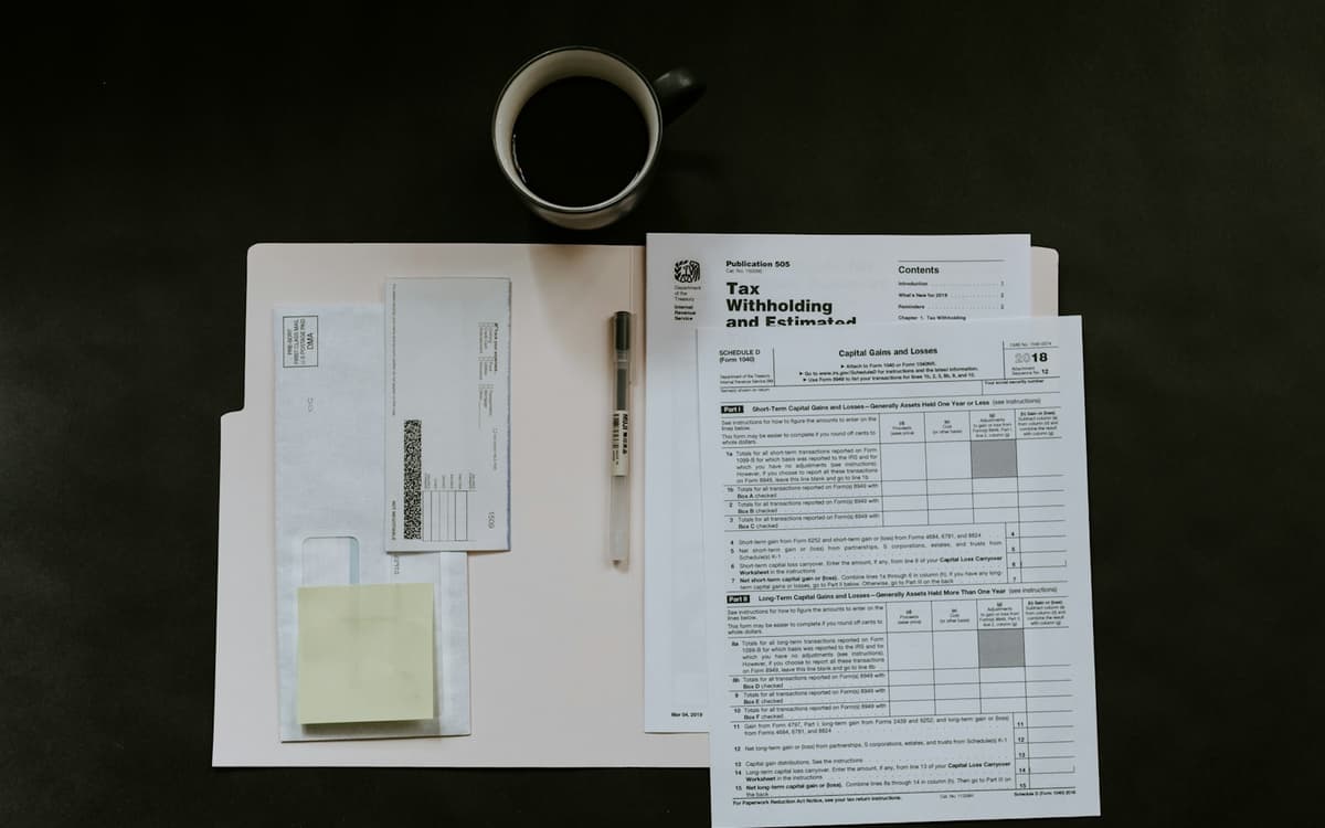 Tax and salary forms laid out on a desk with a pen