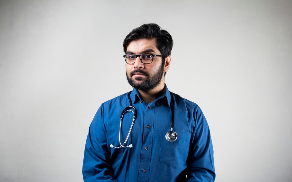 A doctor in a blue shirt with a stethoscope around his neck