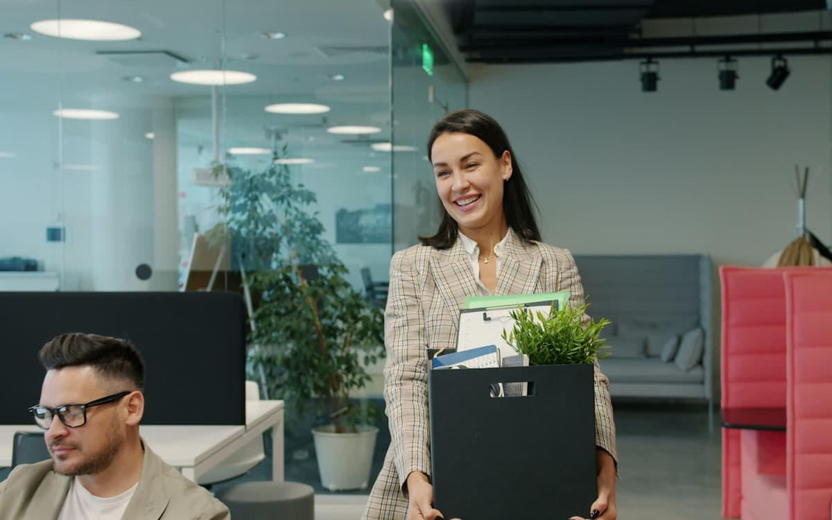 An employee carrying a box of belongings out of an office
