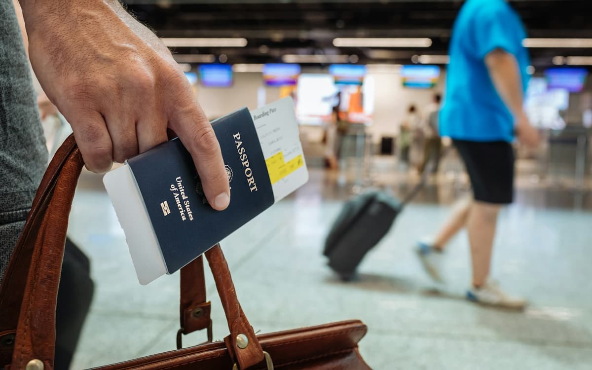 A traveller holding a passport and boarding pass in an airport