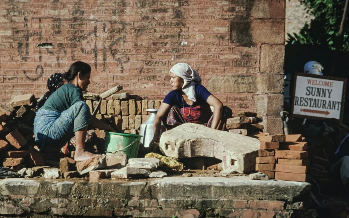 Two women labourers breaking bricks at a building site