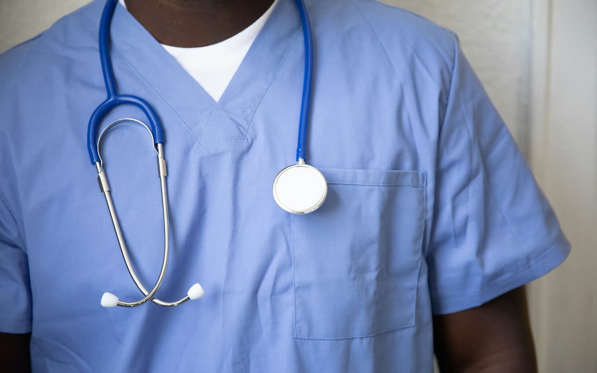 A nurse in blue scrubs with a stethoscope around the neck