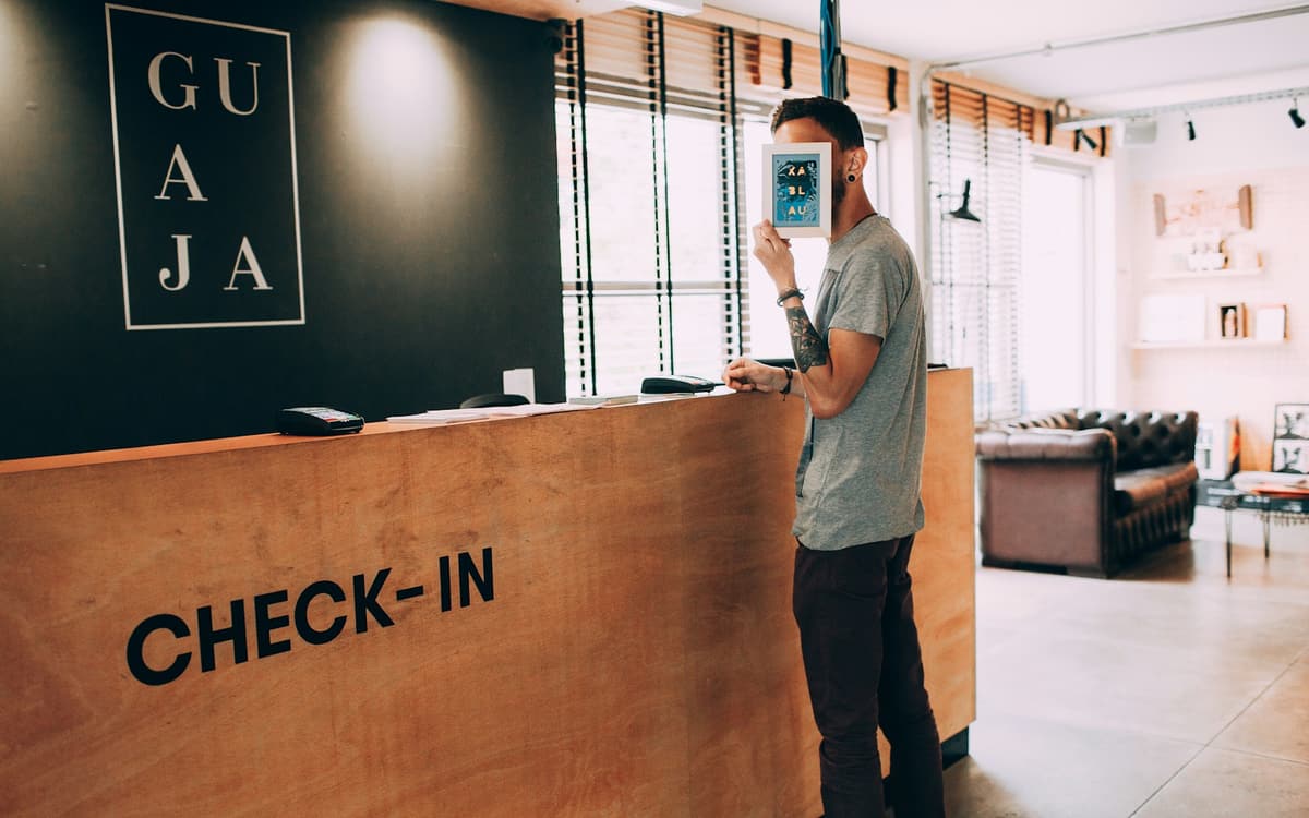 A visitor standing at a wooden check-in desk in a reception area