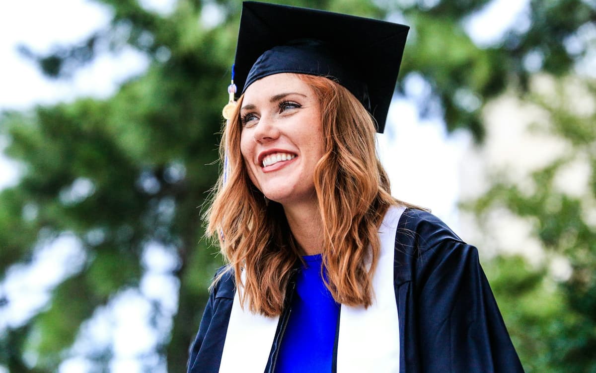 A smiling graduate in an academic gown and cap