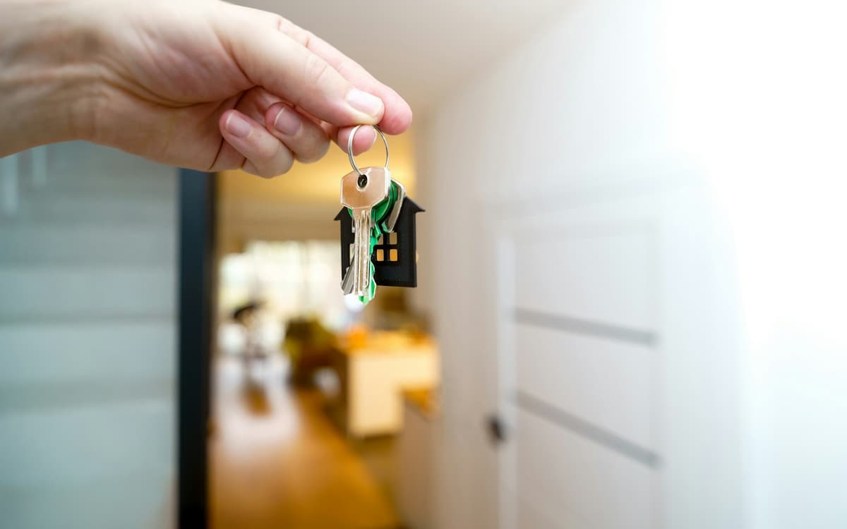 A hand holding house keys in a doorway