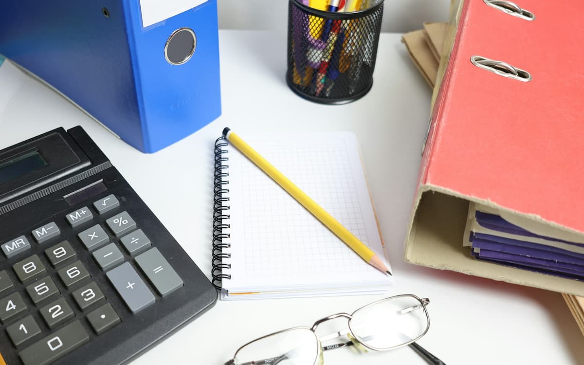 Binders, a calculator and a notebook on a desk