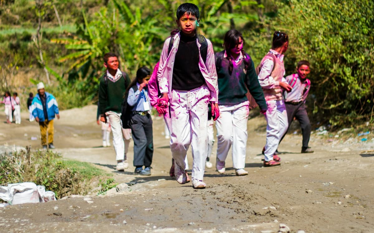School children in uniform walking home along a village road in Nepal