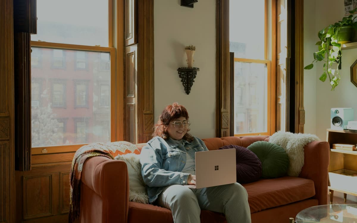 A person working on a laptop from a sofa at home